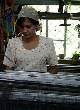 Mary E. Frederickson, Tending an early twentieth century Draper loom made in Massachusetts for use in mills across the Carolinas, Georgia, and Alabama, Margilan, Uzbekistan, 2006.