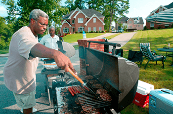 Annual block party, Stone Mountain, Georgia, July 18, 2004. James Giffin Jr. grills burgers and dogs in Southland Subdivision while his father James Giffin Sr. looks on. Both are originally from Chicago. Southland is a predominately African American middle to upper middle class neighborhood. Photograph by HIP Incorporated © 2004.