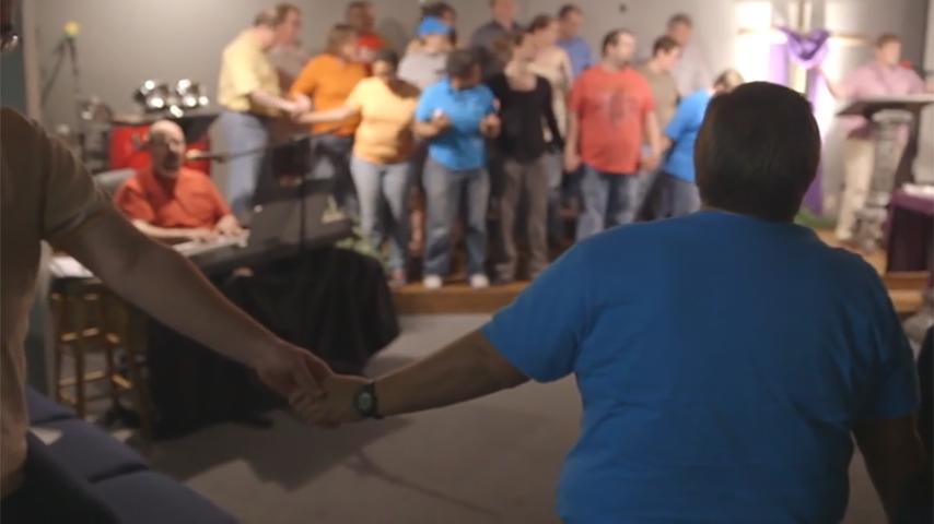 two congregants holding hands inside Safe Harbor Family Church, Flowood, Mississippi, ca. 2014