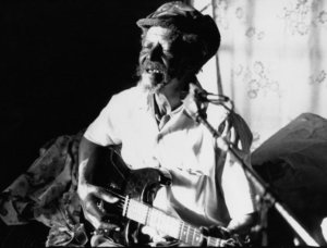 Cecil Barfield playing the electric guitar and singing into a microphone.