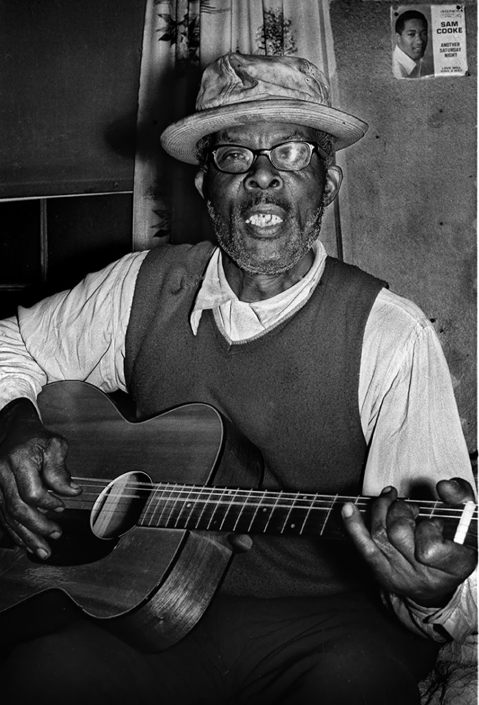 Jim Bunkley holding a guitar and singing.