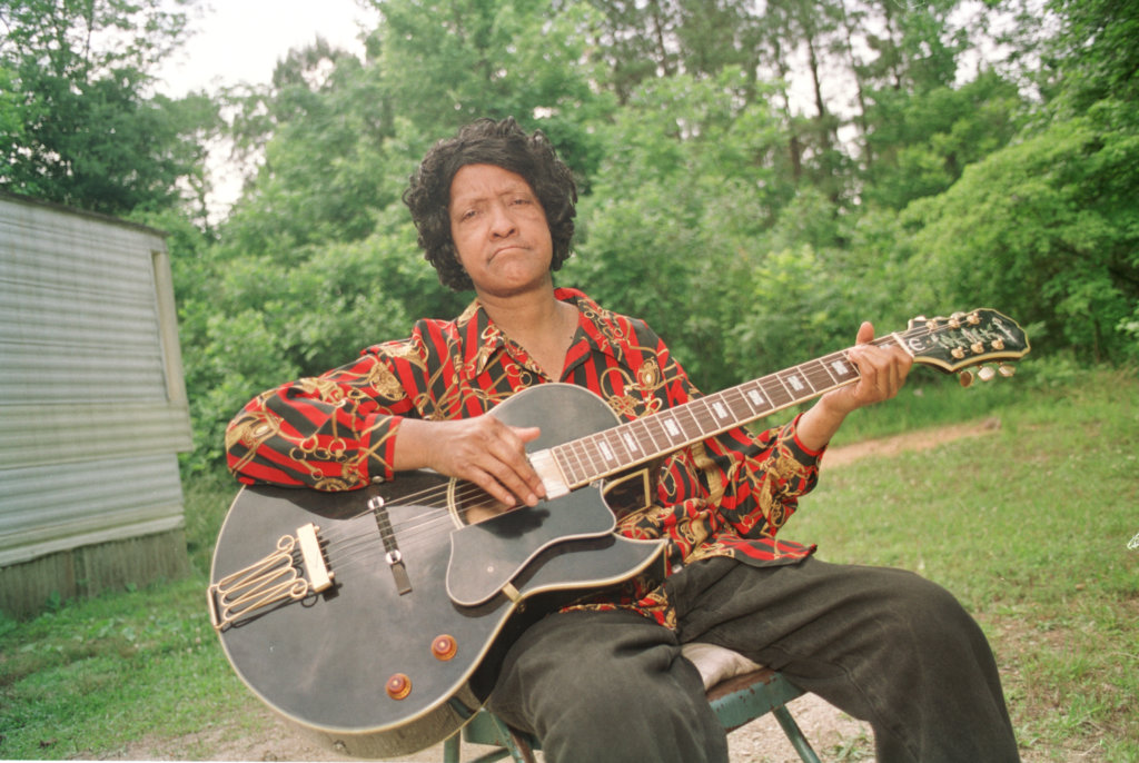 Precious Bryant holds a guitar and looks at the camera.