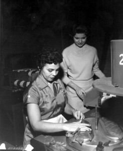 A lady watches a woman rolling a cigar in a factory, Tampa, Florida, 1963.