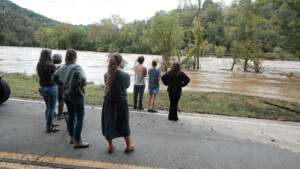 People looking at the raging French Broad River during Hurricane Helene.