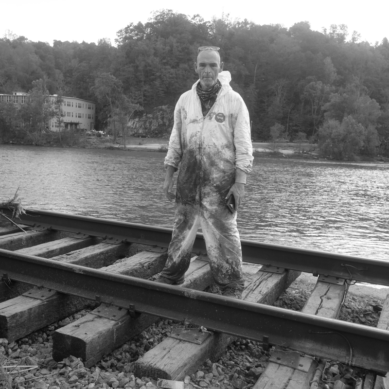 Portrait of Joe Bruneau, community resident and artist, on railroad tracks overlooking river.