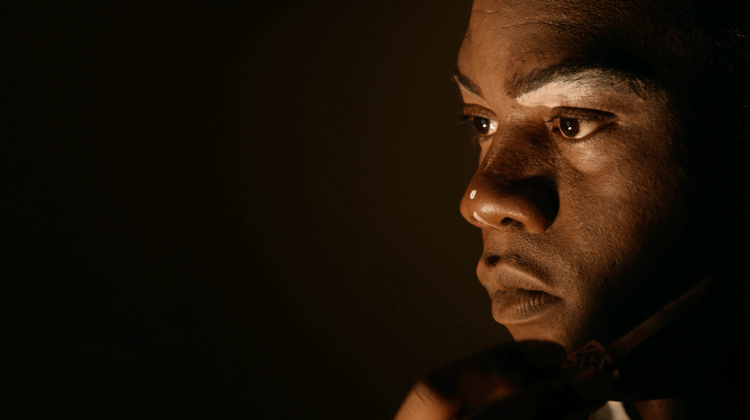 Close up silhouette of Black man with partial face makeup.