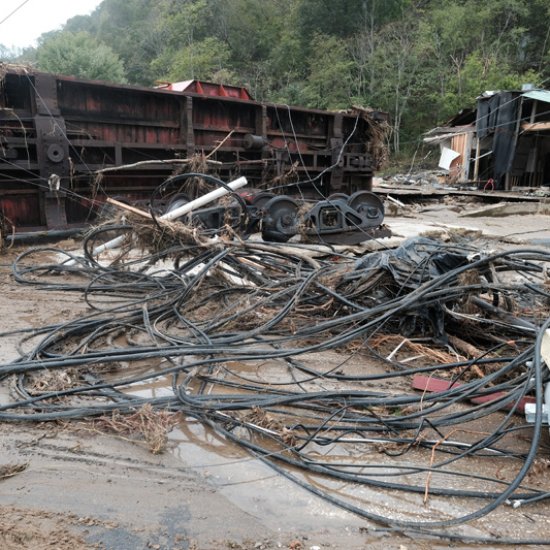Turned over railroad car that housed WART radio station with tangled PVC pipe and destroyed house in background.